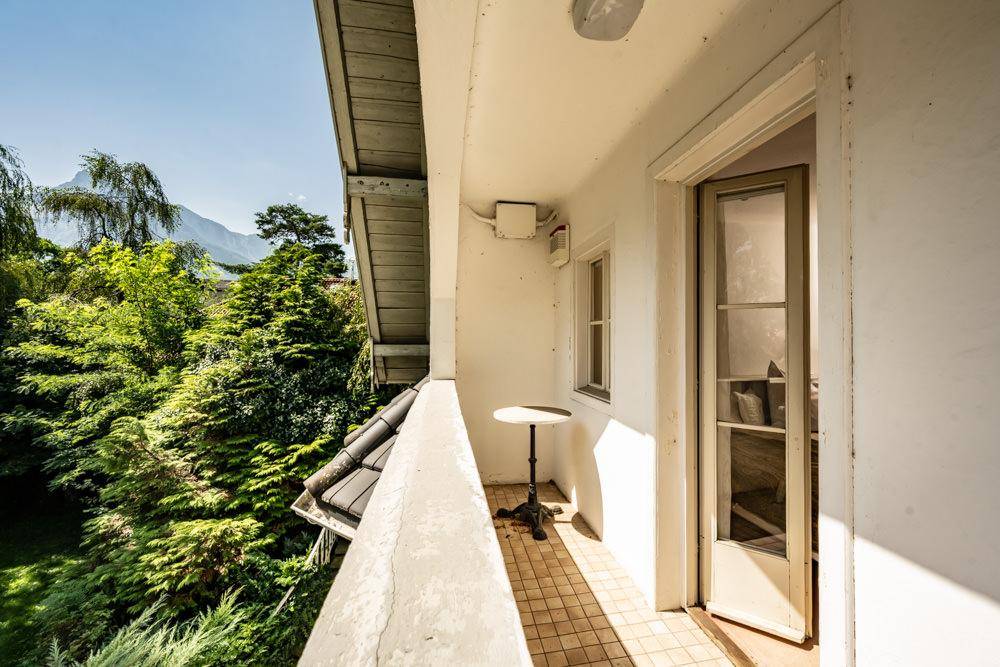 Sonniger Balkon mit Fliesenboden, kleinem Tisch und weitem Blick ins Grüne und auf die Berge.