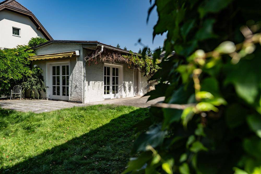 Nebengebäude mit großen Fenstertüren und einer kleinen Rasenfläche im Vordergrund.