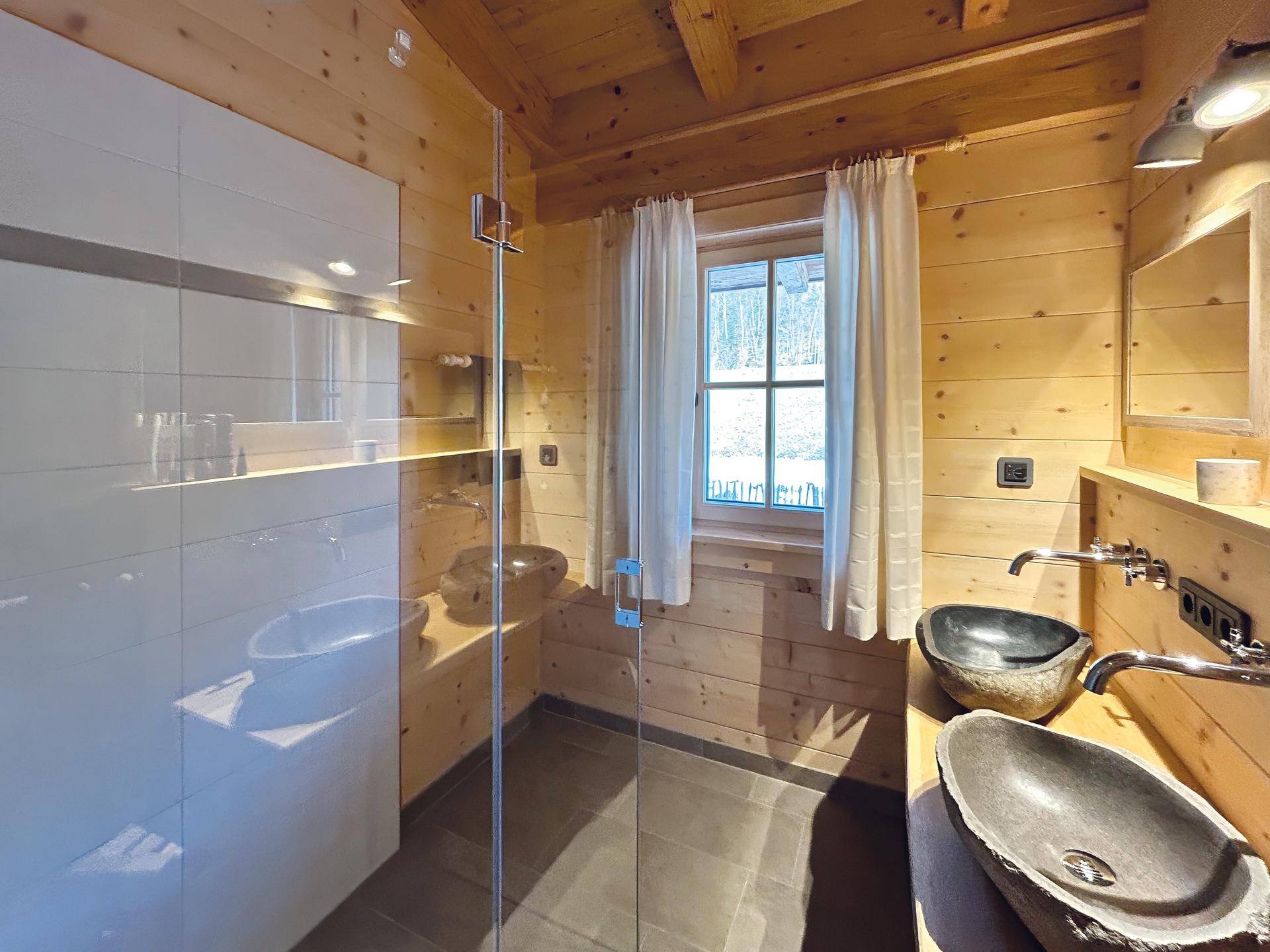 Modernes Badezimmer mit begehbarer Dusche, Doppelwaschbecken und Holzwänden.