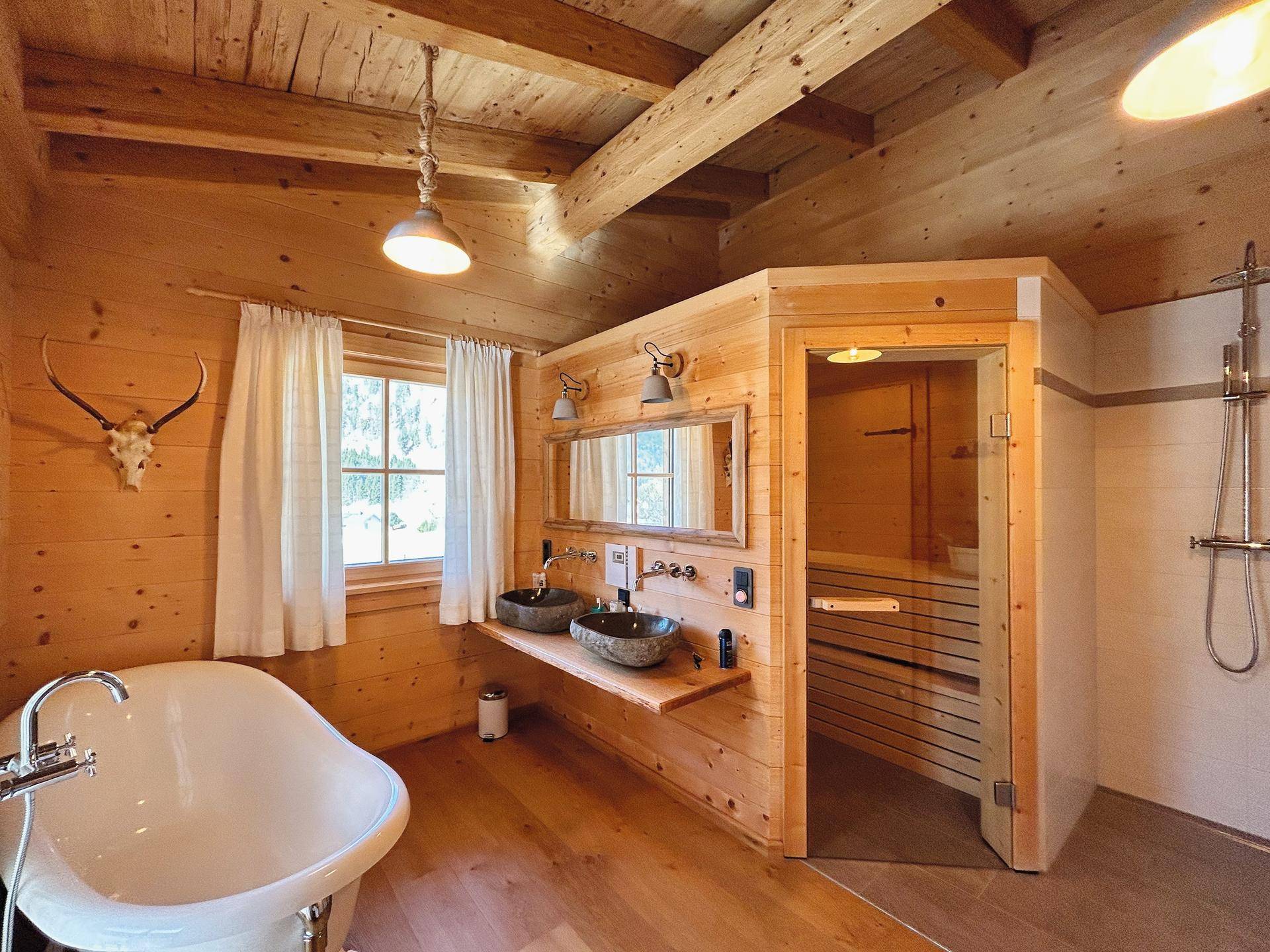 Geräumiges Badezimmer im Holzdesign mit freistehender Badewanne und integrierter Sauna.