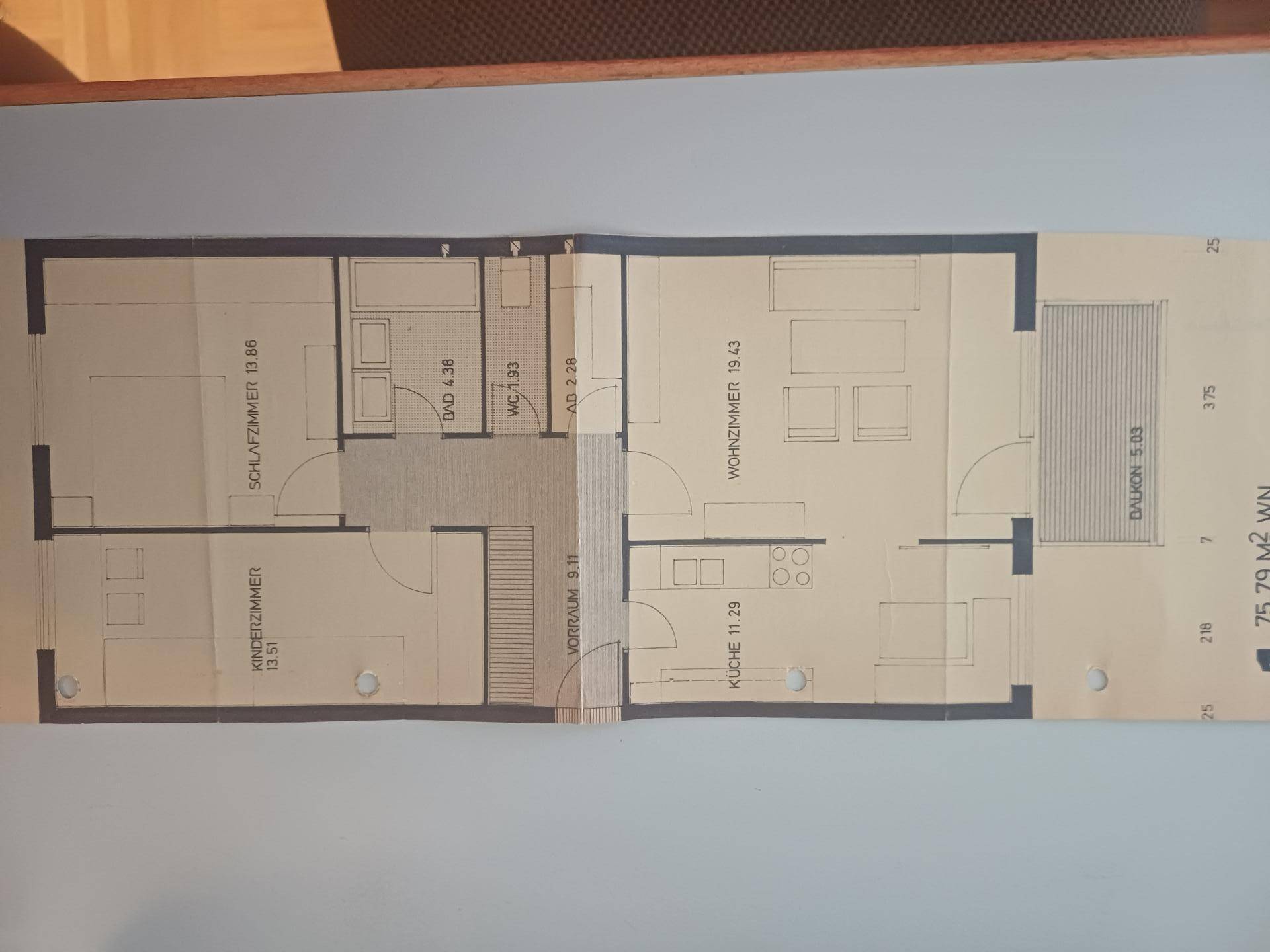 Grundriss einer Wohnung mit Schlafzimmer, Kinderzimmer, Bad, separatem WC und offenem Wohnbereich mit Balkon.