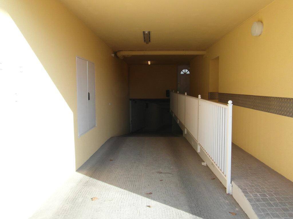 Zufahrt zu einer Tiefgarage mit Rampe und gelben Wänden.