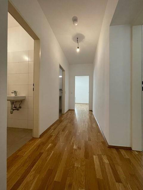 Heller Flur mit Parkettboden, der zu verschiedenen Räumen der Wohnung führt.