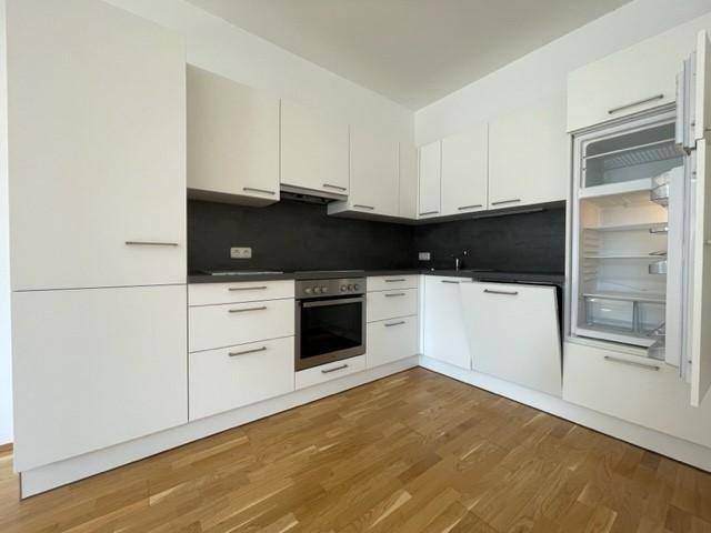 Moderne Einbauküche mit weißen Schränken, dunkler Arbeitsplatte und integrierten Geräten.