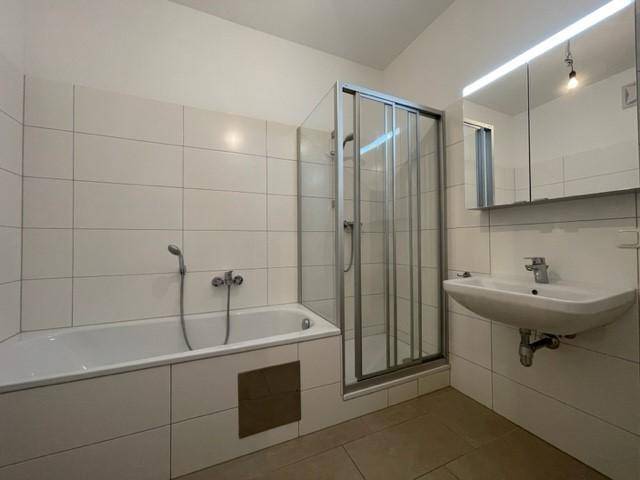 Modernes Badezimmer mit Badewanne, Duschkabine, Waschbecken und Spiegelschrank.
