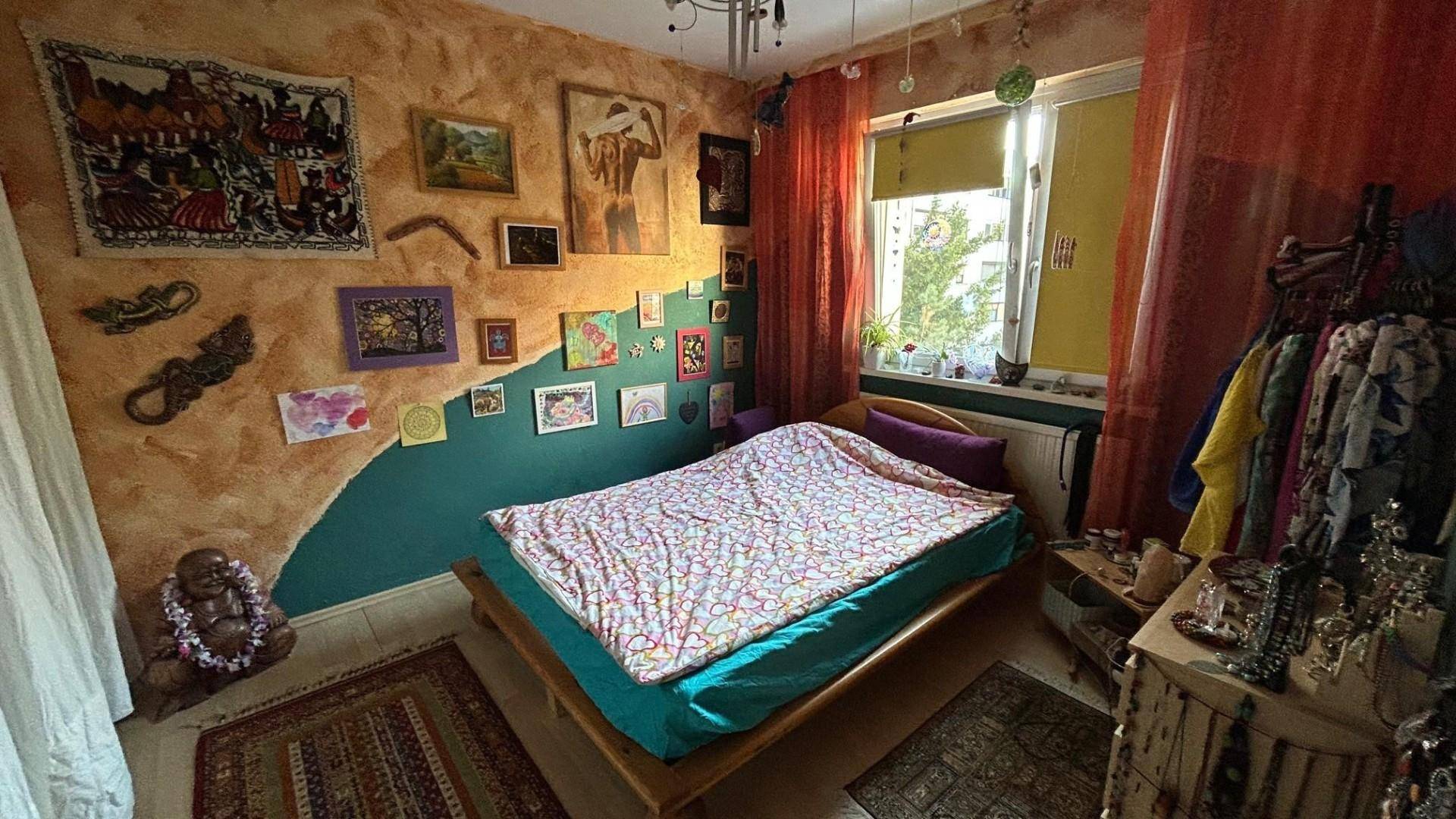 Schlafzimmer mit farbenfroher Wandgestaltung, einem Doppelbett und viel persönlicher Dekoration.