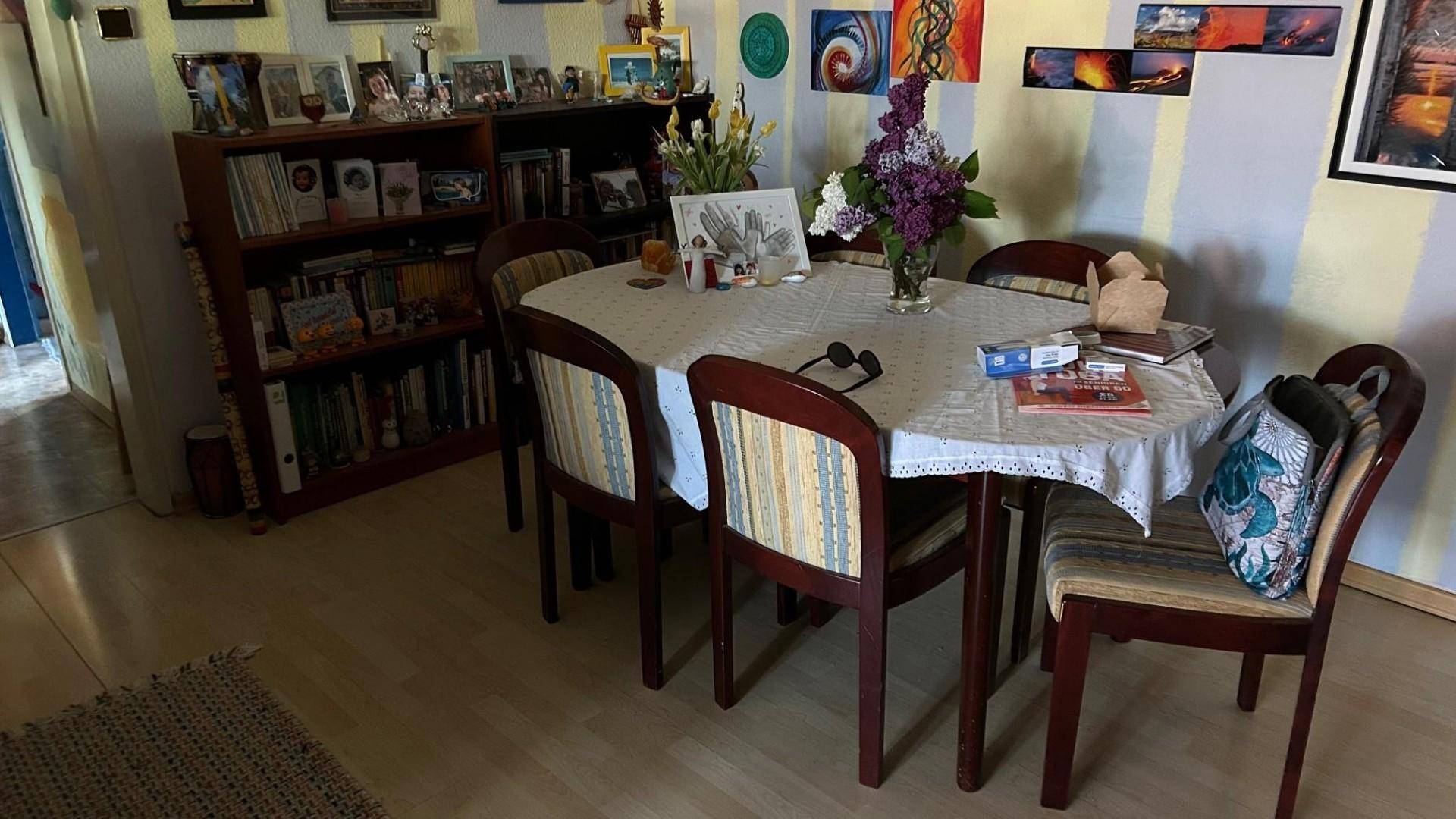 Essbereich mit ovalem Esstisch, passenden Stühlen und einem Bücherregal an der Wand.