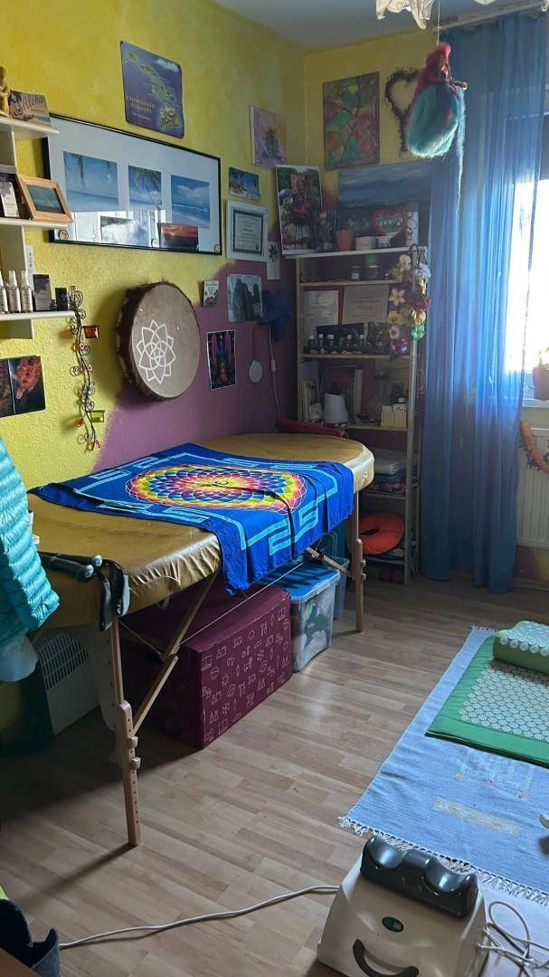 Vielseitiger Raum mit Massageliege, Regalen und farbenfroher Dekoration, ideal als Arbeitszimmer.