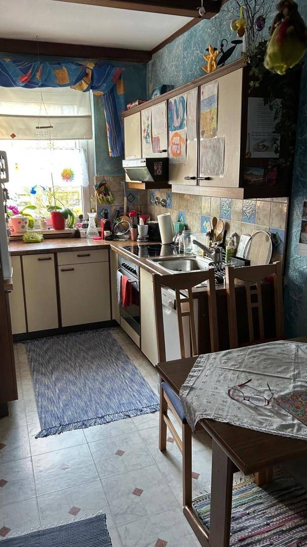 Funktionale Küche mit hellen Schränken, Spüle und einem Fenster mit Blick nach draußen.