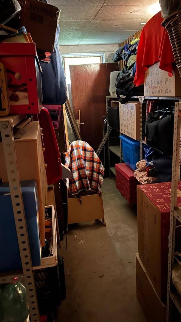 Überfüllter Abstellraum mit vielen Kartons, Regalen und persönlichen Gegenständen.