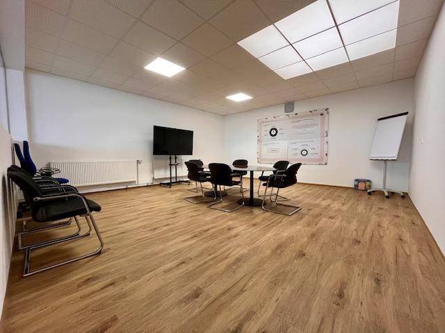 Konferenzraum mit großem Bildschirm, Besprechungstisch und Whiteboard, ideal für Präsentationen.