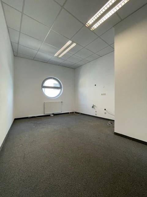 Büro mit einzigartigem Rundfenster, Heizkörper und Teppichboden, bietet eine besondere Arbeitsatmosphäre.