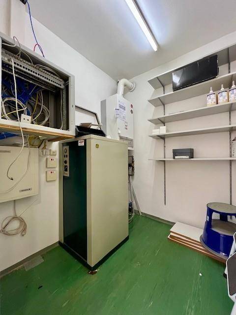 Technikraum mit Serverrack, Heizungsanlage und Regalen, funktional und gut organisiert.
