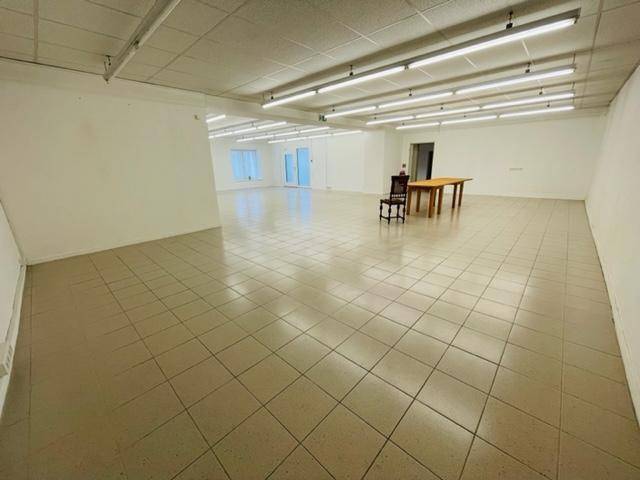 Großer, sauberer Raum mit Fliesenboden und Fenstern im Hintergrund, bietet viel Platz.
