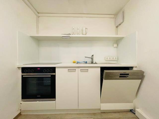 Nahaufnahme einer kompakten Küchenzeile mit integriertem Backofen und Spülmaschine.