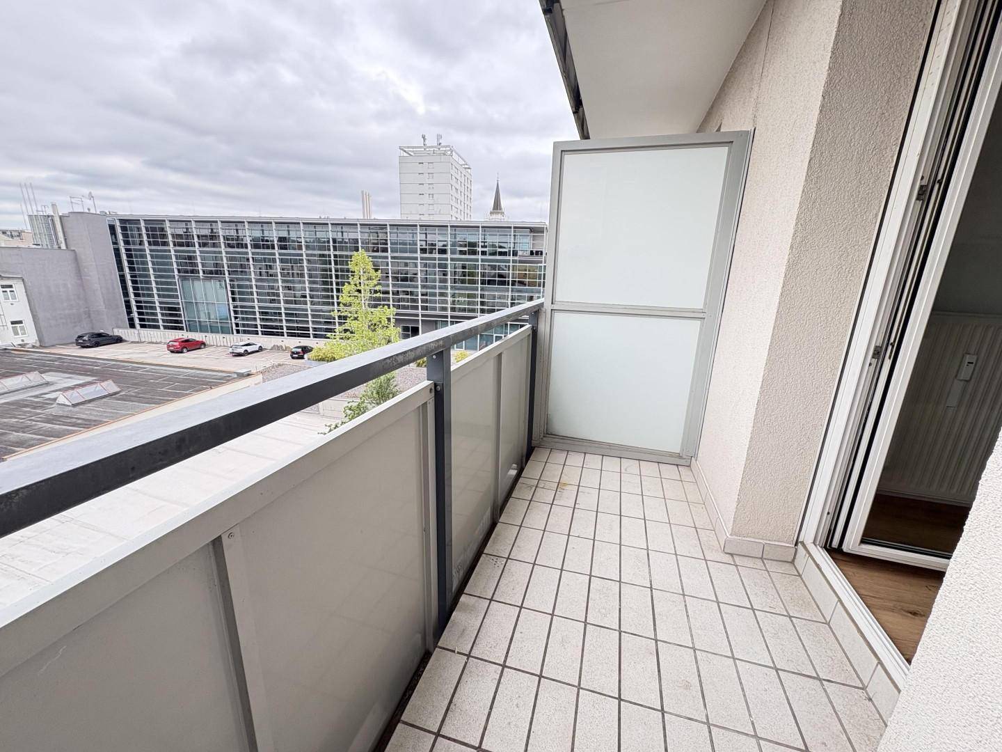 Balkon mit Fliesenboden und Blick auf die umliegende städtische Bebauung und Gebäude.