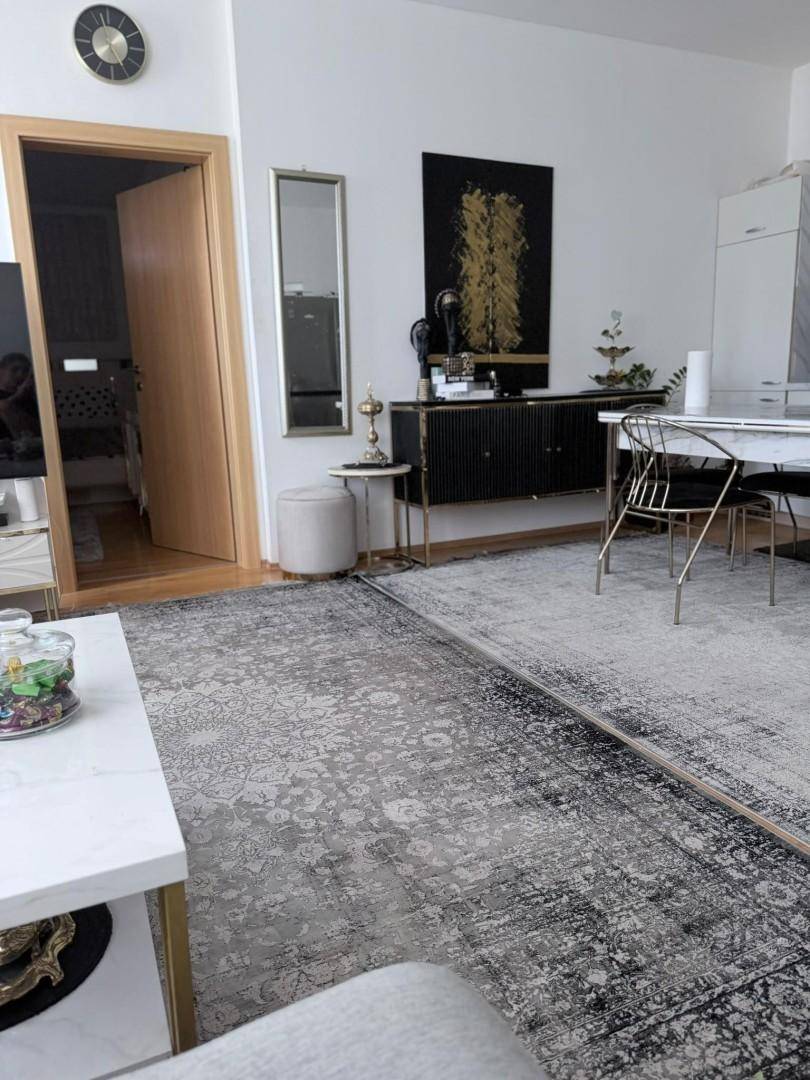 Wohnbereich mit stilvollem Sideboard, großem Teppich und Zugang zu weiteren Räumen.