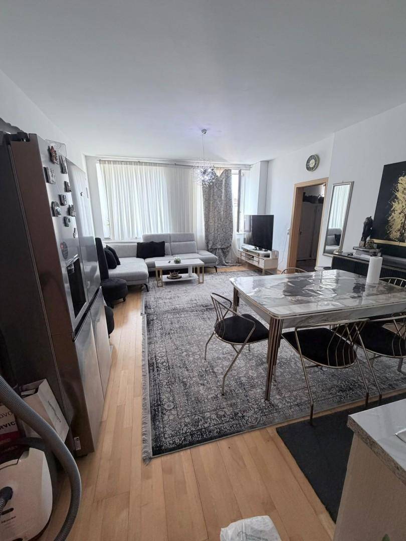 Geräumiger offener Wohn- und Essbereich mit großem Teppich, Sofa und Esstisch auf Holzparkett.