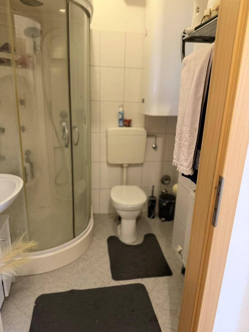 Funktionales Badezimmer mit Duschkabine, WC und weißen Fliesen.
