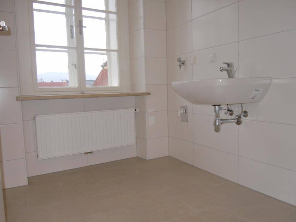 Modernes Badezimmer mit Waschbecken, weißen Fliesen und einem Fenster für natürliche Belüftung.