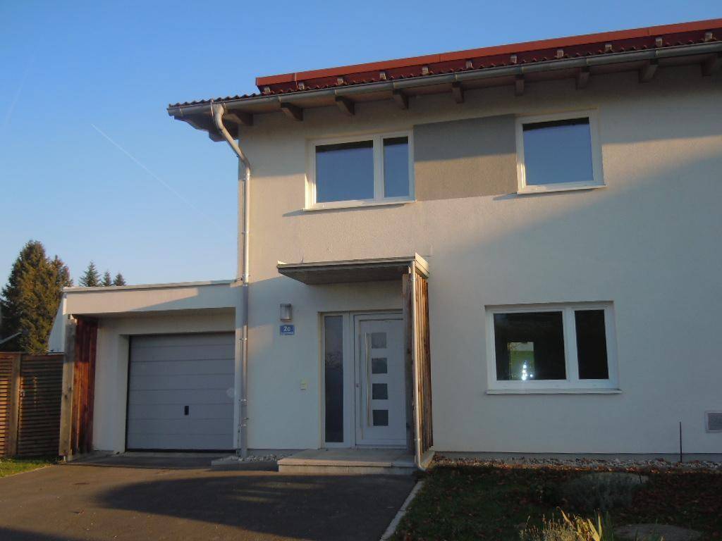 Nahaufnahme des Hauseingangs und der integrierten Garage eines modernen Reihenhauses bei Sonnenschein.