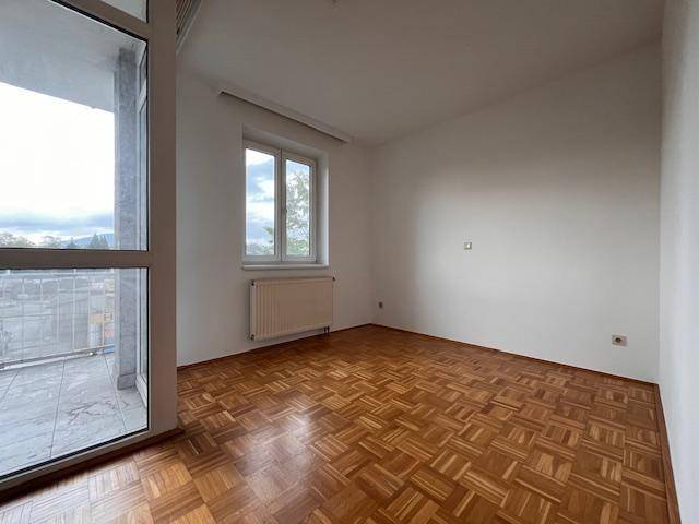 Helles Schlafzimmer mit Parkettboden, Fenster und direktem Zugang zu einem Balkon für frische Luft.