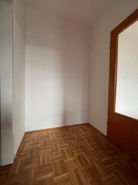 Kleiner, heller Flurbereich mit Parkettboden und Holztür, der einen einladenden Eingang bietet.