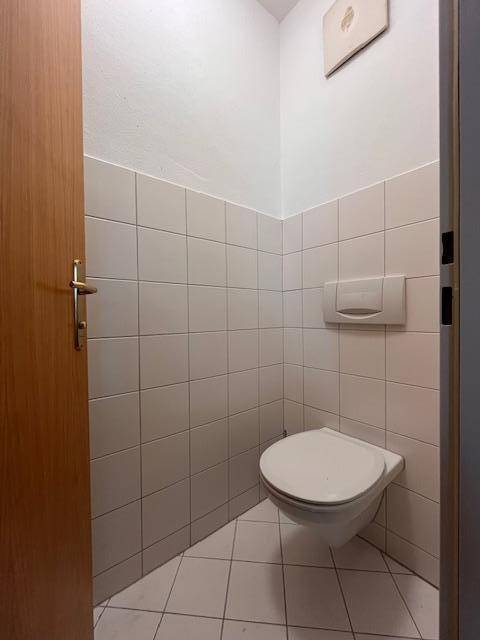 Separate Toilette mit Wand-WC und weißen Fliesen, sauber und praktisch gestaltet.
