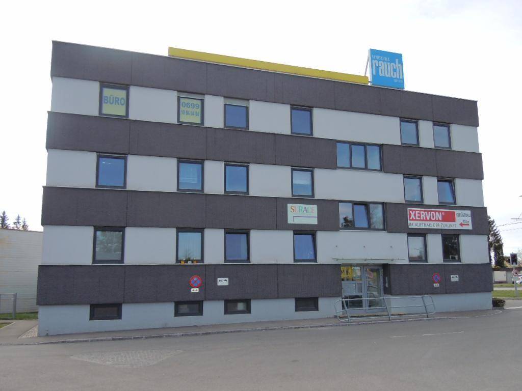 Mehrstöckiges Geschäftsgebäude mit moderner Fassade, vielen Fenstern und Werbeschildern an der Außenseite.