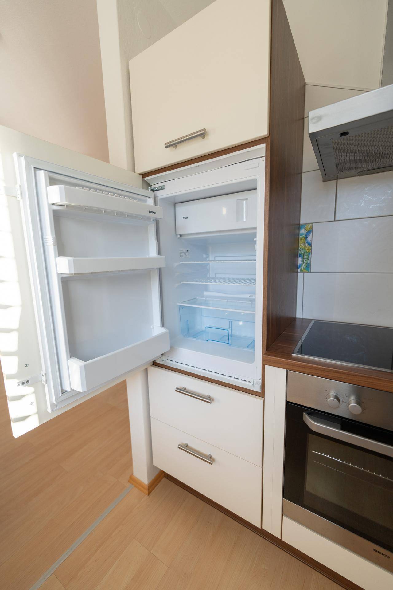 Integrierter Kühlschrank in der Küche mit geöffneter Tür, zeigt das Gefrierfach.