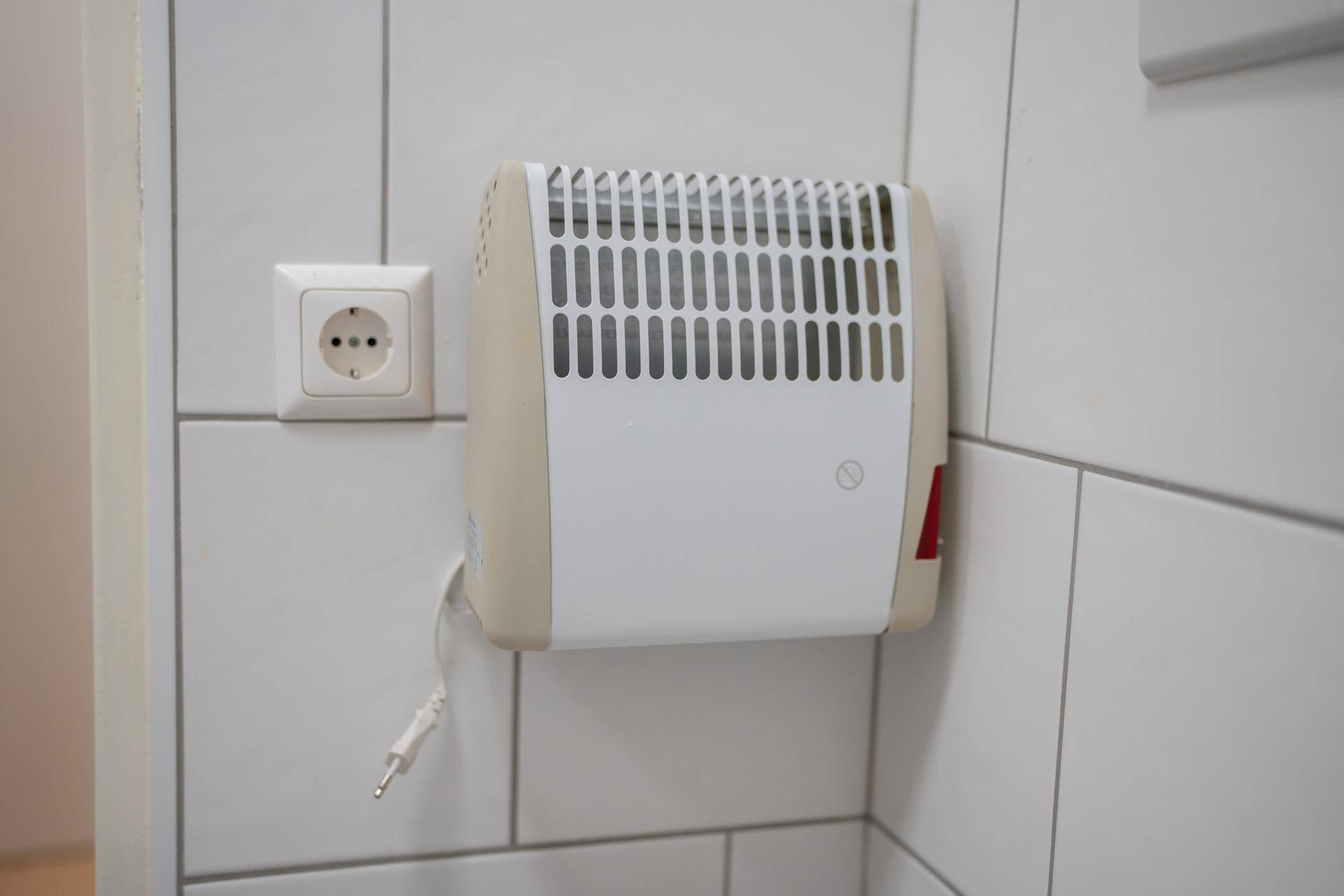 Nahaufnahme eines elektrischen Heizlüfters an der Wand im Badezimmer.