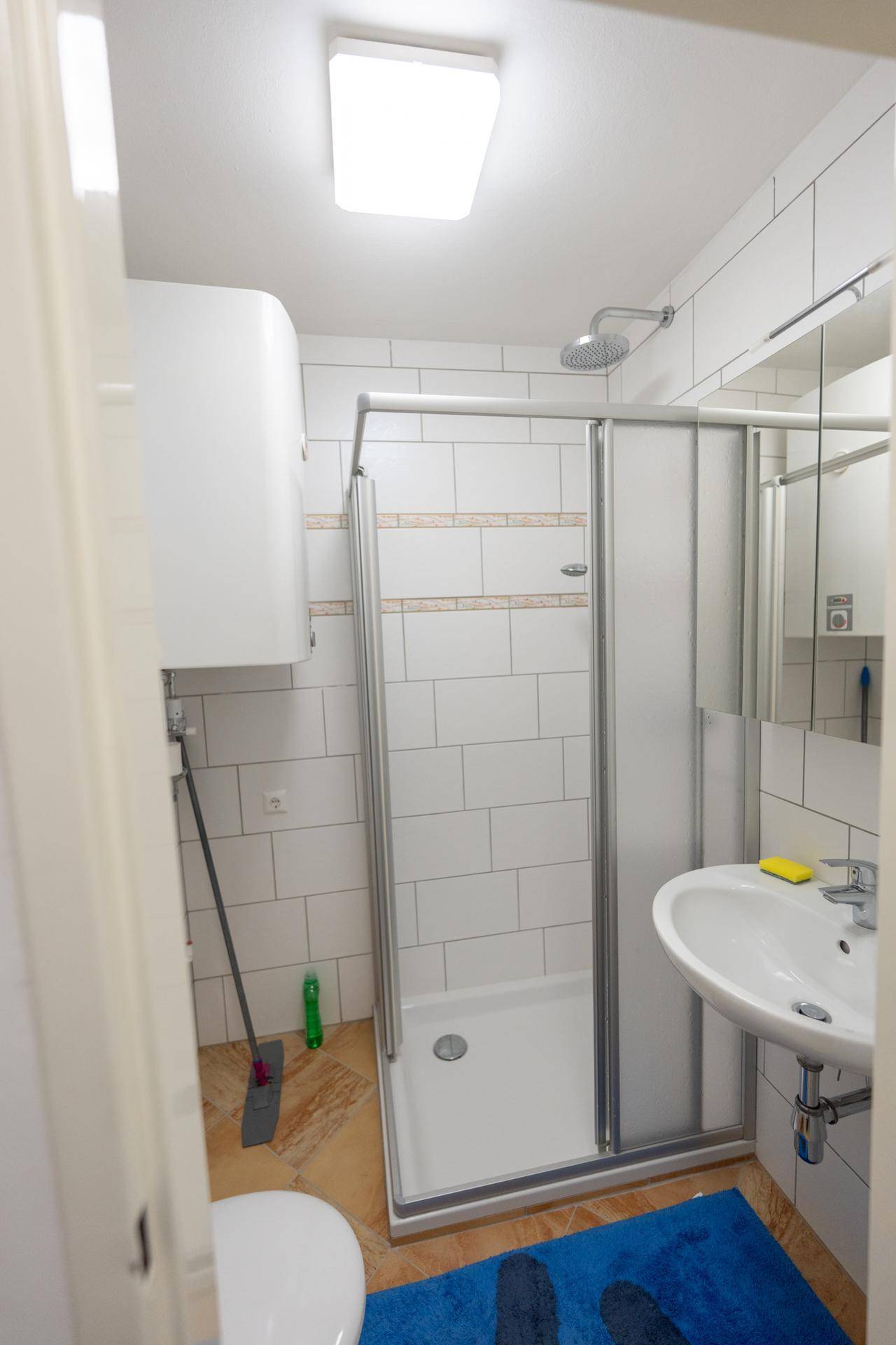 Funktionales Badezimmer mit Duschkabine, Waschbecken und Toilette.