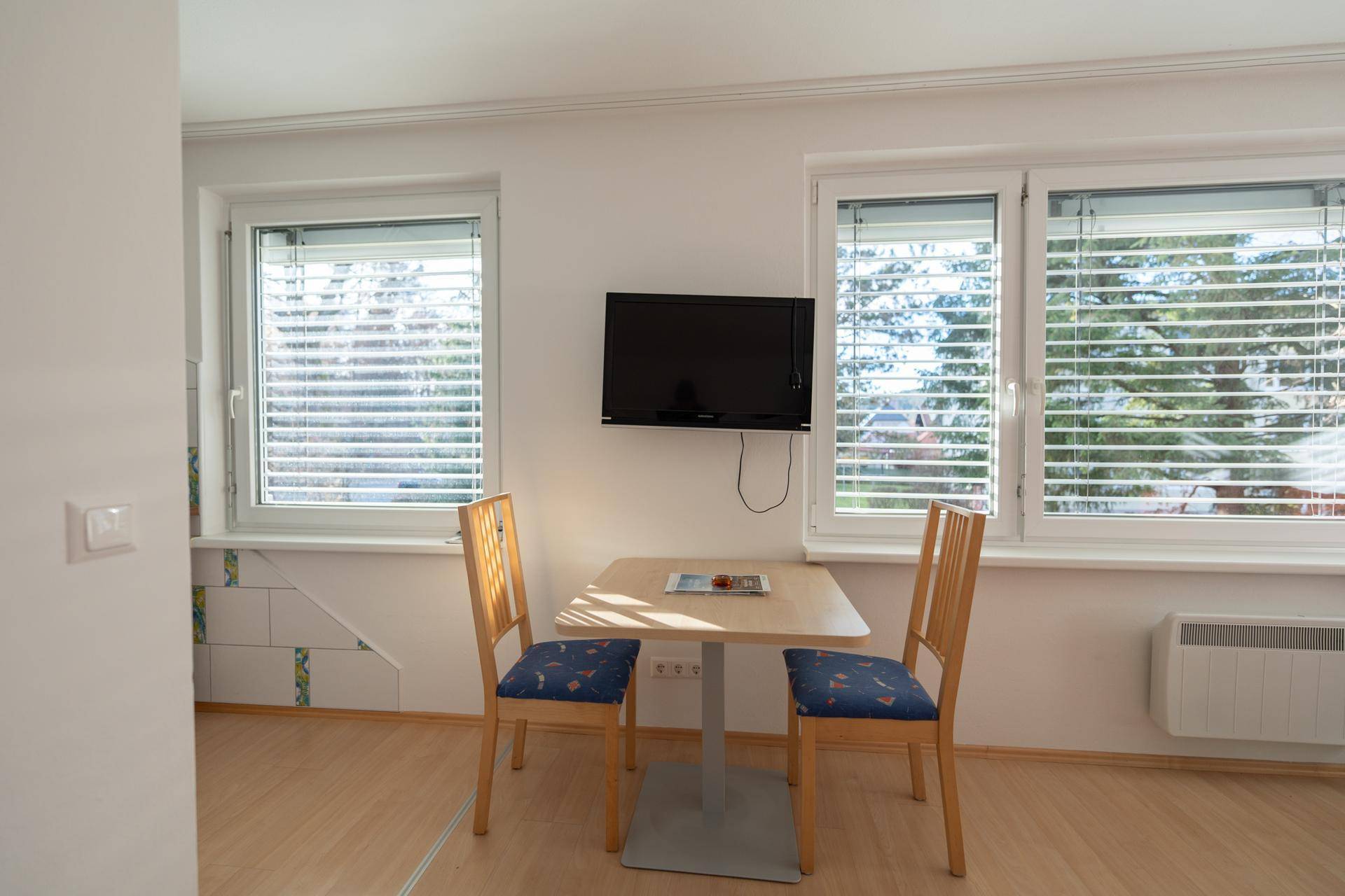 Essbereich im Wohnzimmer mit kleinem Tisch, Stühlen und Blick aus dem Fenster.