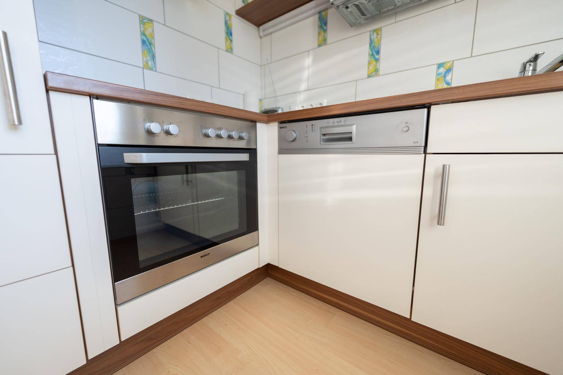 Nahaufnahme von Backofen und Geschirrspüler in der Einbauküche mit Holztheke.