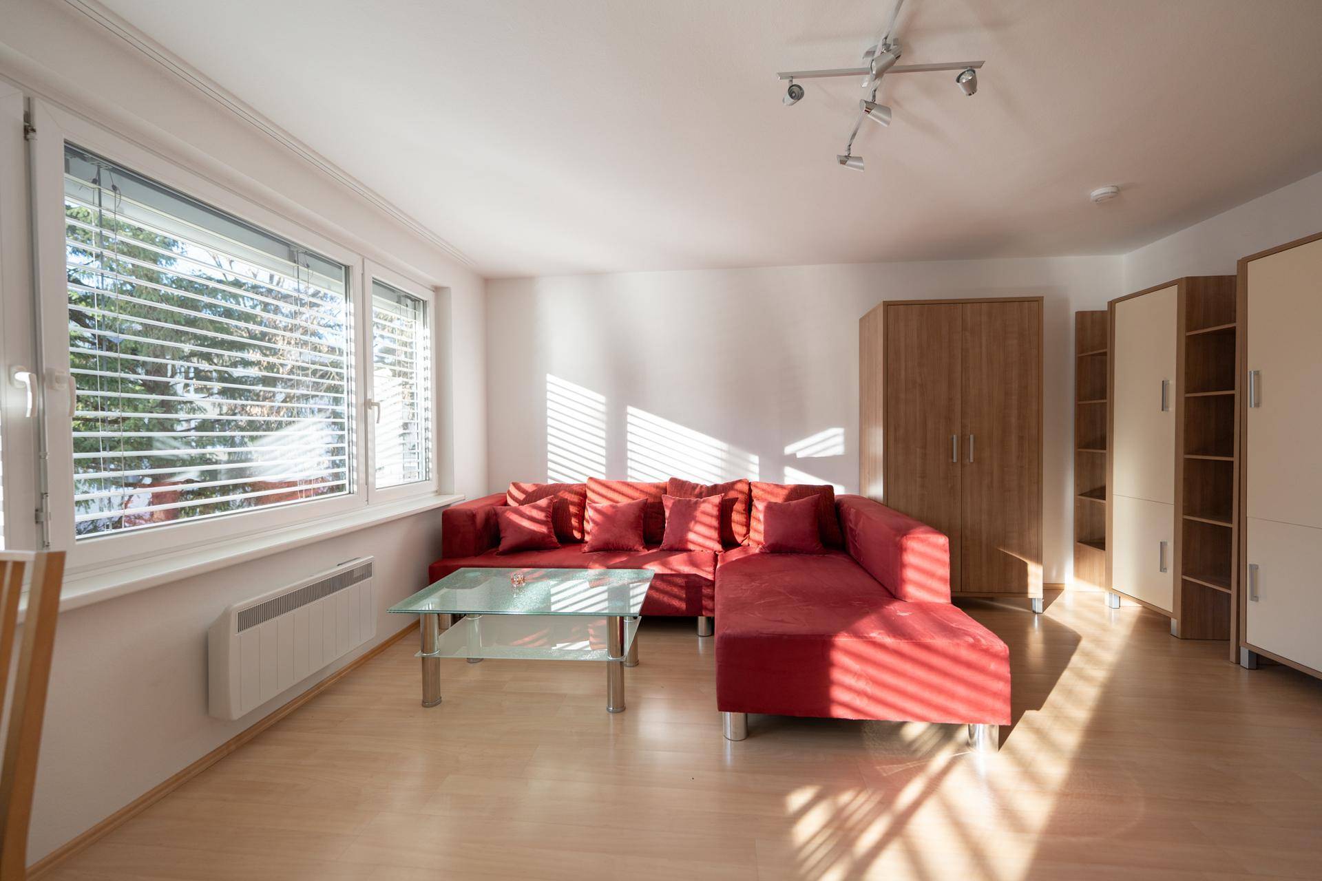 Helles Wohnzimmer mit rotem Sofa, großen Fenstern und viel natürlichem Lichteinfall.