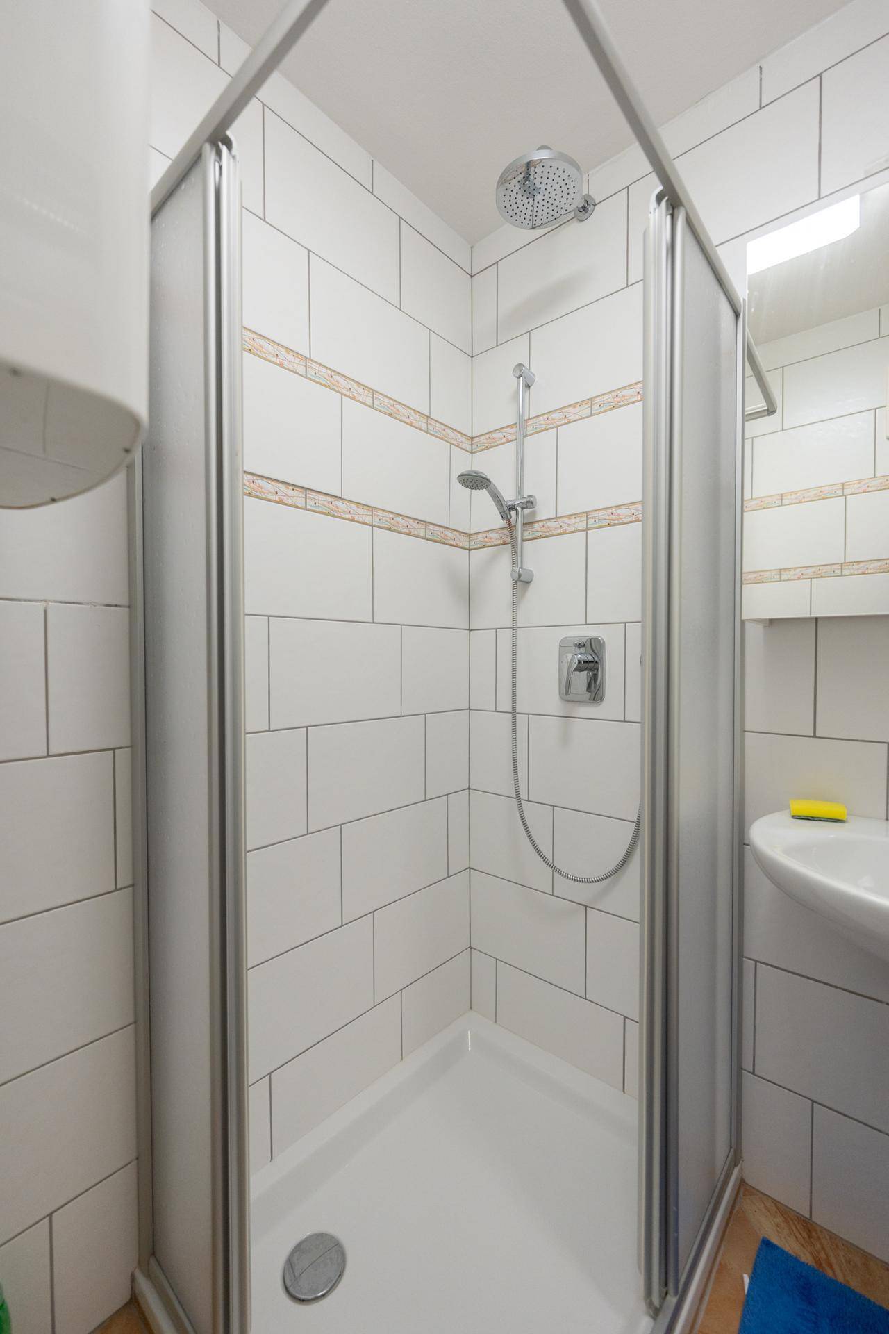 Nahaufnahme der Duschkabine mit Duschkopf und Armatur.