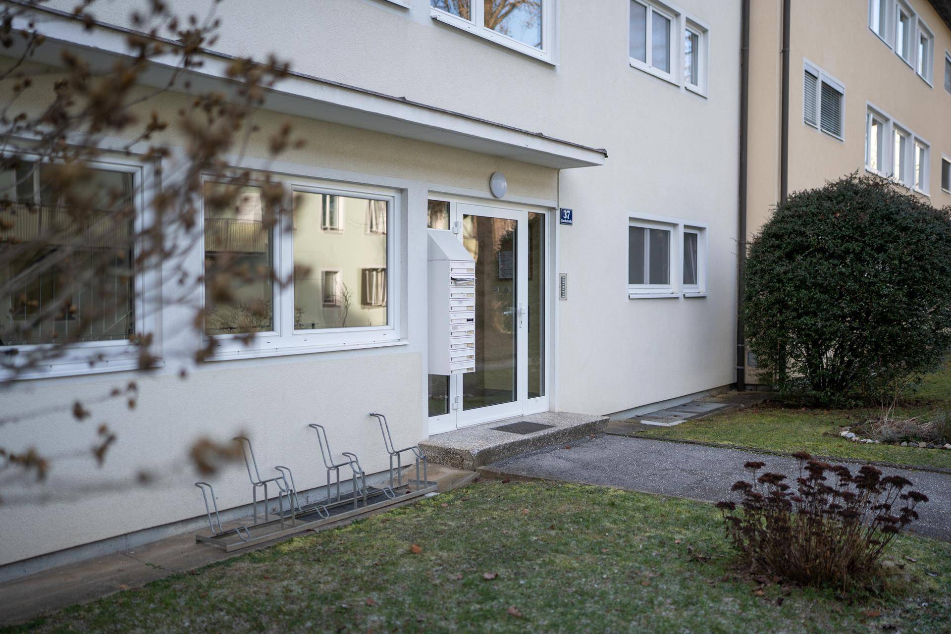 Eingangsbereich des Mehrfamilienhauses mit Briefkästen, Fahrradständern und einer modernen Glastür.