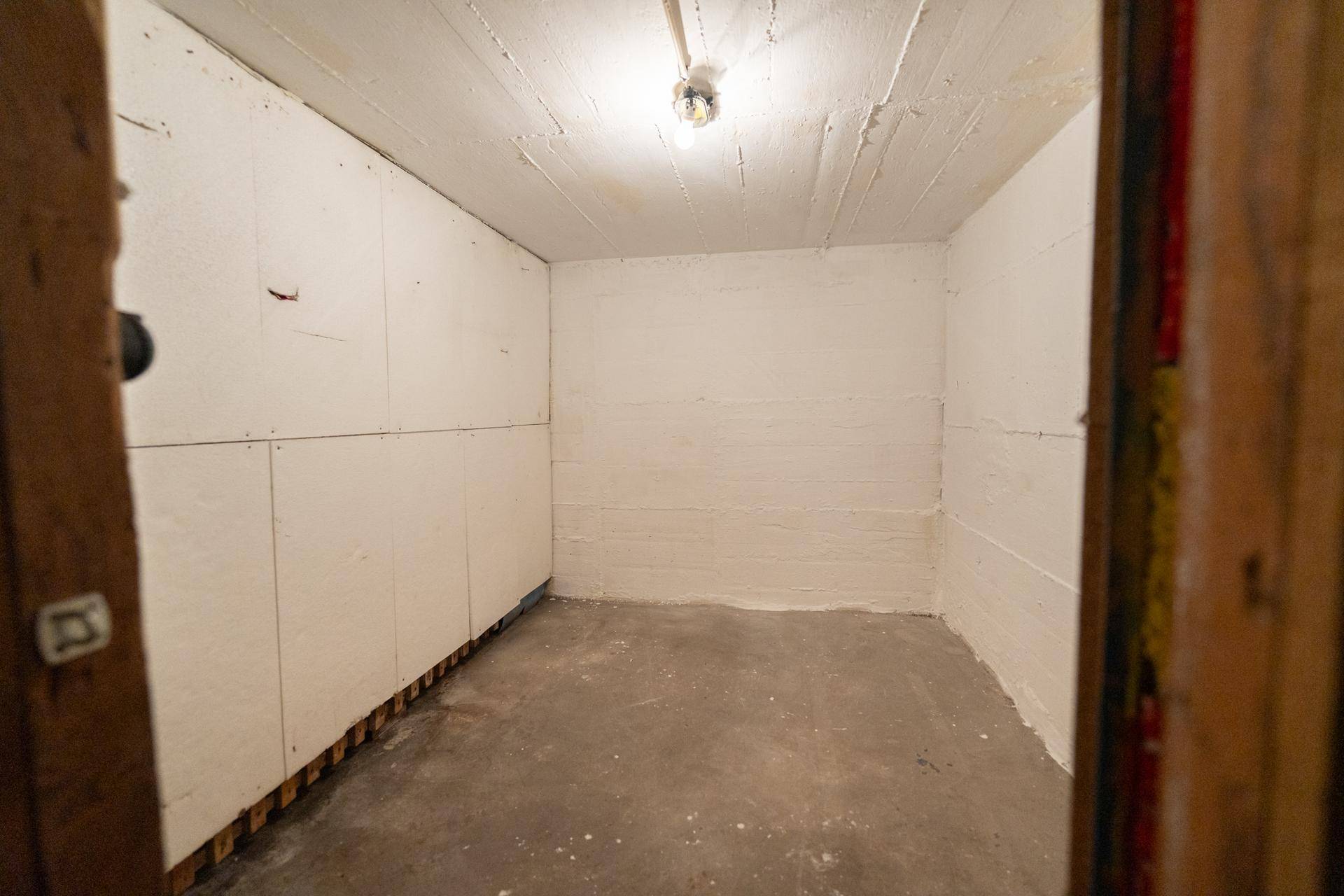 Leerer Abstellraum im Keller mit einfachen Wänden und Betonboden.