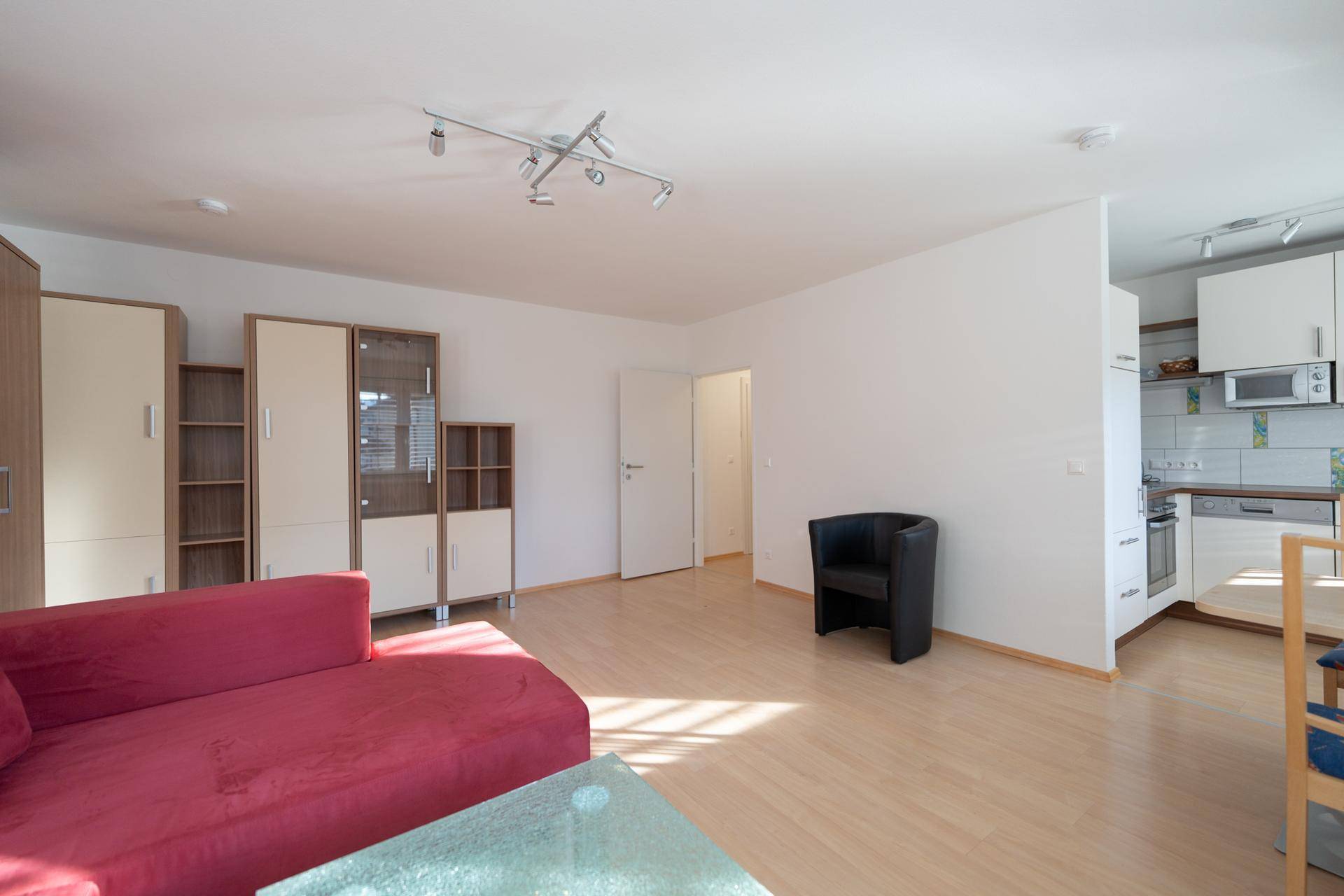 Offener Wohnbereich mit rotem Sofa und Blick auf den Essbereich und die Küche.