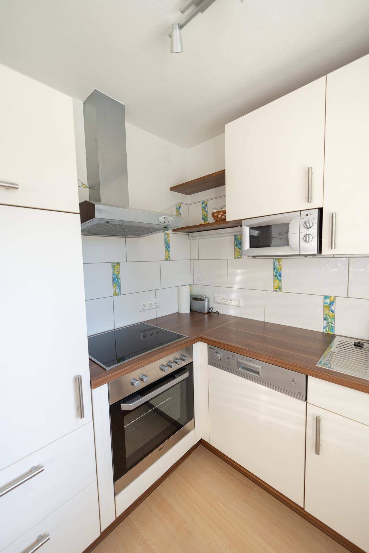 Küchenzeile mit modernen Einbaugeräten, Induktionskochfeld und Dunstabzugshaube.