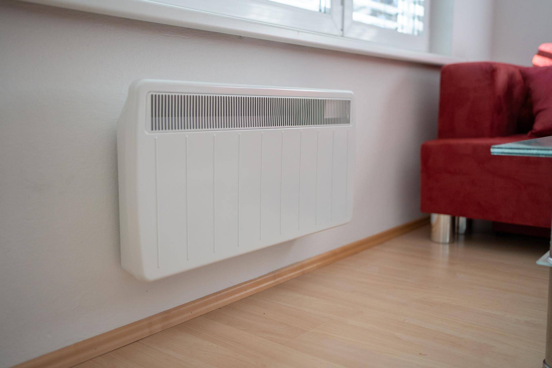 Nahaufnahme eines modernen Heizkörpers unter einem Fenster im Wohnbereich.