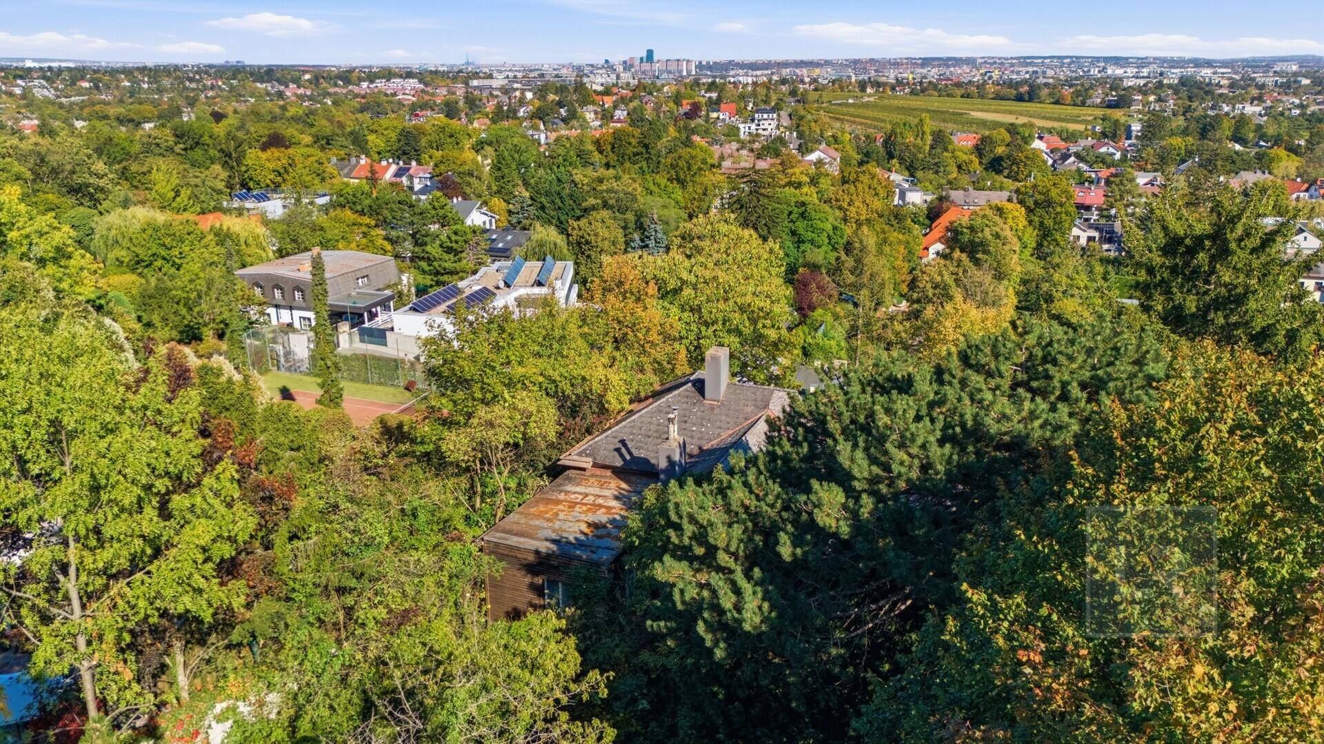 Weitläufige Luftaufnahme des Anwesens mit üppiger Vegetation und der Stadt in der Ferne.