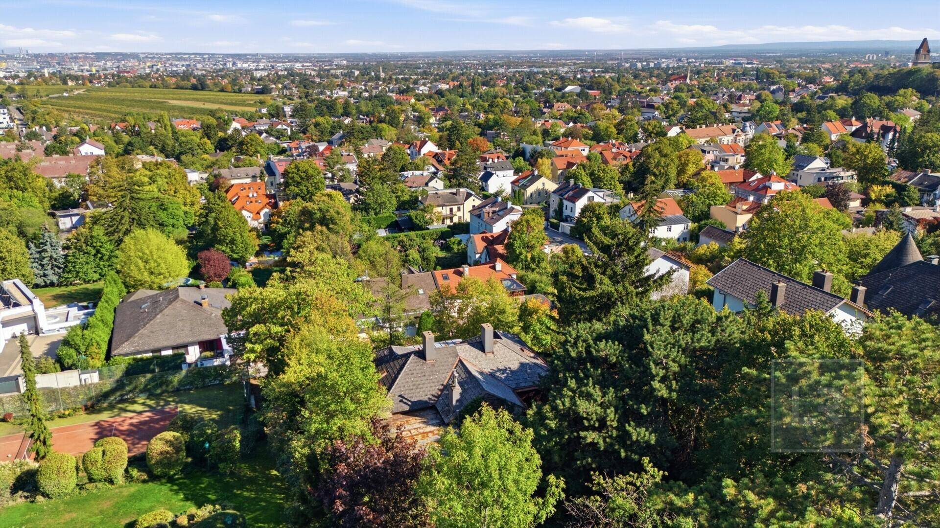 Luftaufnahme des Hauses inmitten grüner Bäume mit einem weiten Blick über die Wohngegend.