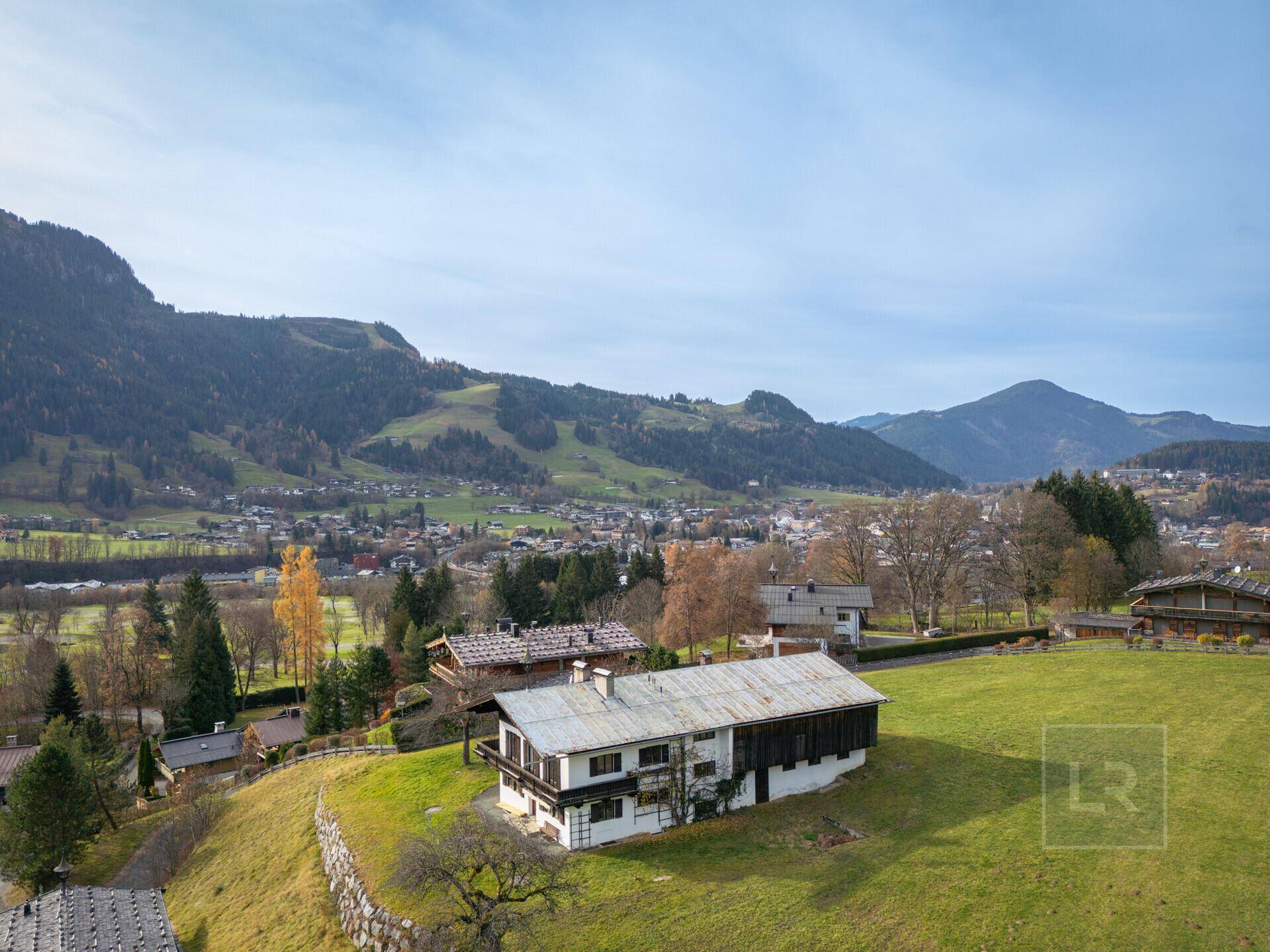 Weitläufige Ansicht der Immobilien in einer hügeligen Landschaft mit einem Dorf im Tal und Bergen.