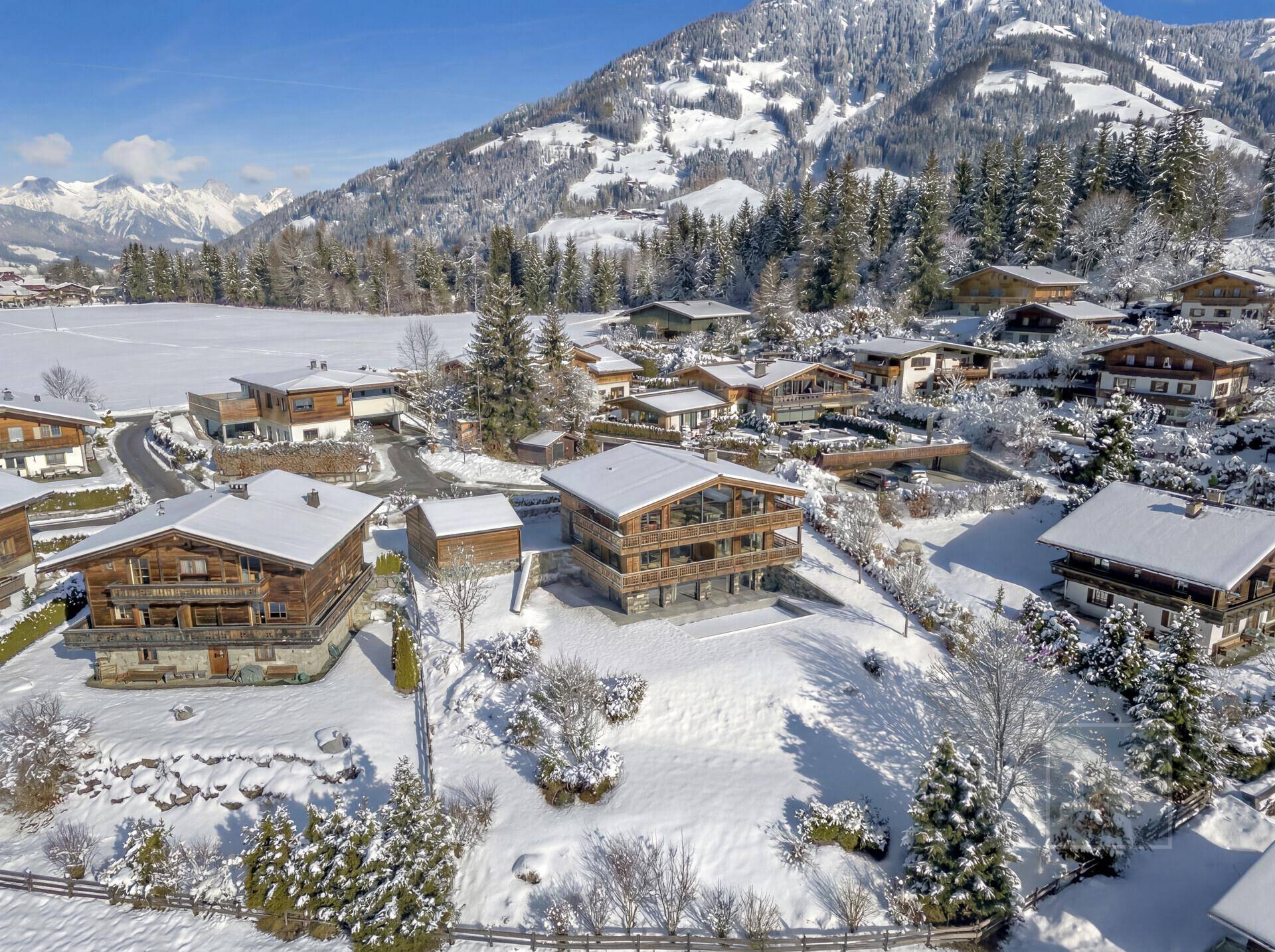 Panoramablick auf ein exklusives Holzchalet inmitten einer idyllischen, verschneiten Alpenlandschaft.