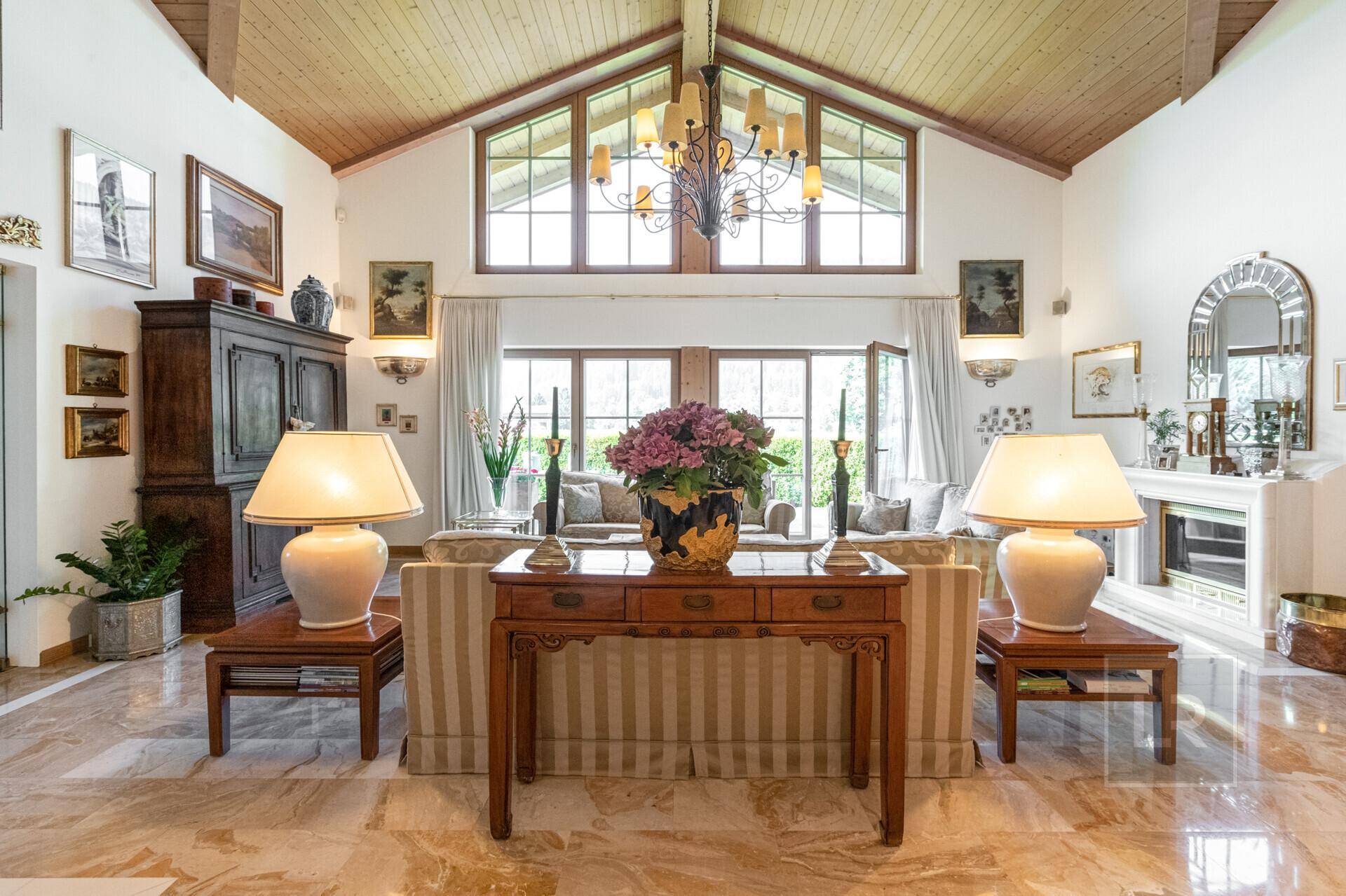Elegantes Wohnzimmer mit hohen Decken, Marmorboden und großen Fenstern, die viel Licht hereinlassen.