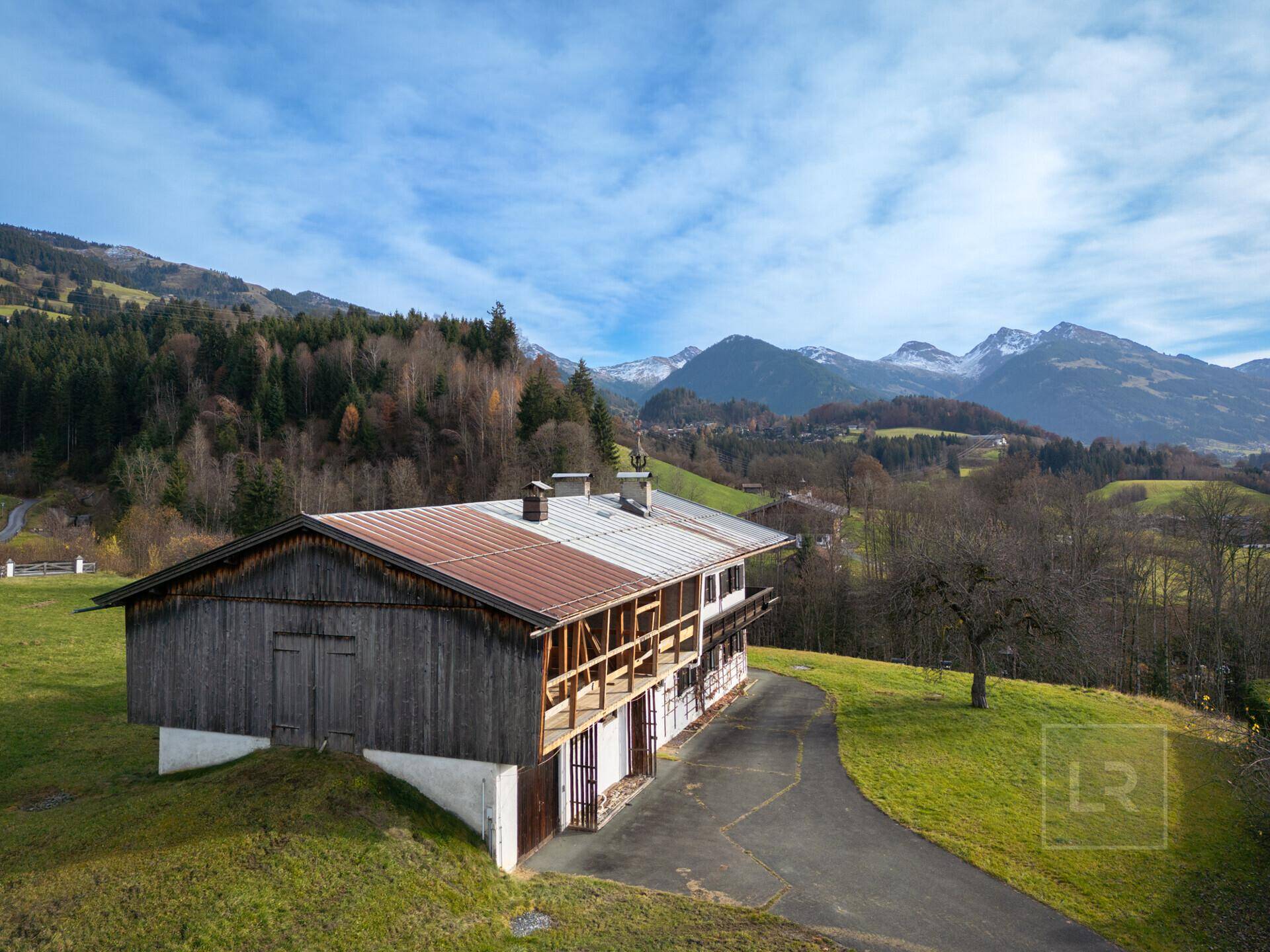 Seitenansicht eines traditionellen Holzgebäudes mit Balkonen und Blick auf die schneebedeckten Berge.