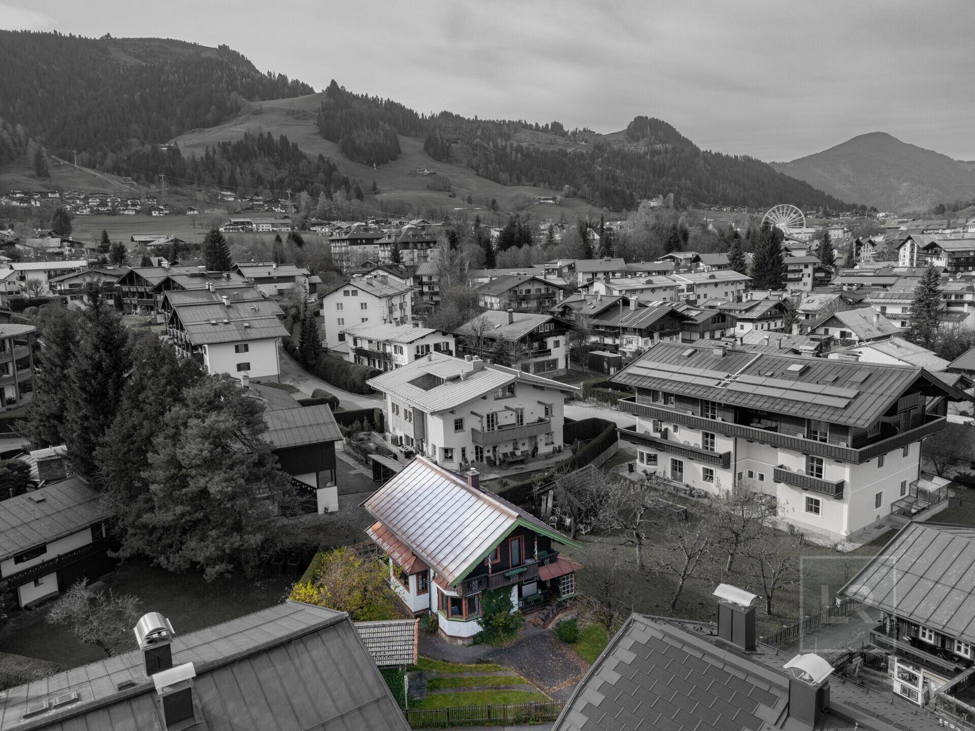 Luftaufnahme des Hauses in einer Wohngegend mit Bergkulisse und teilweise farbiger Hervorhebung.