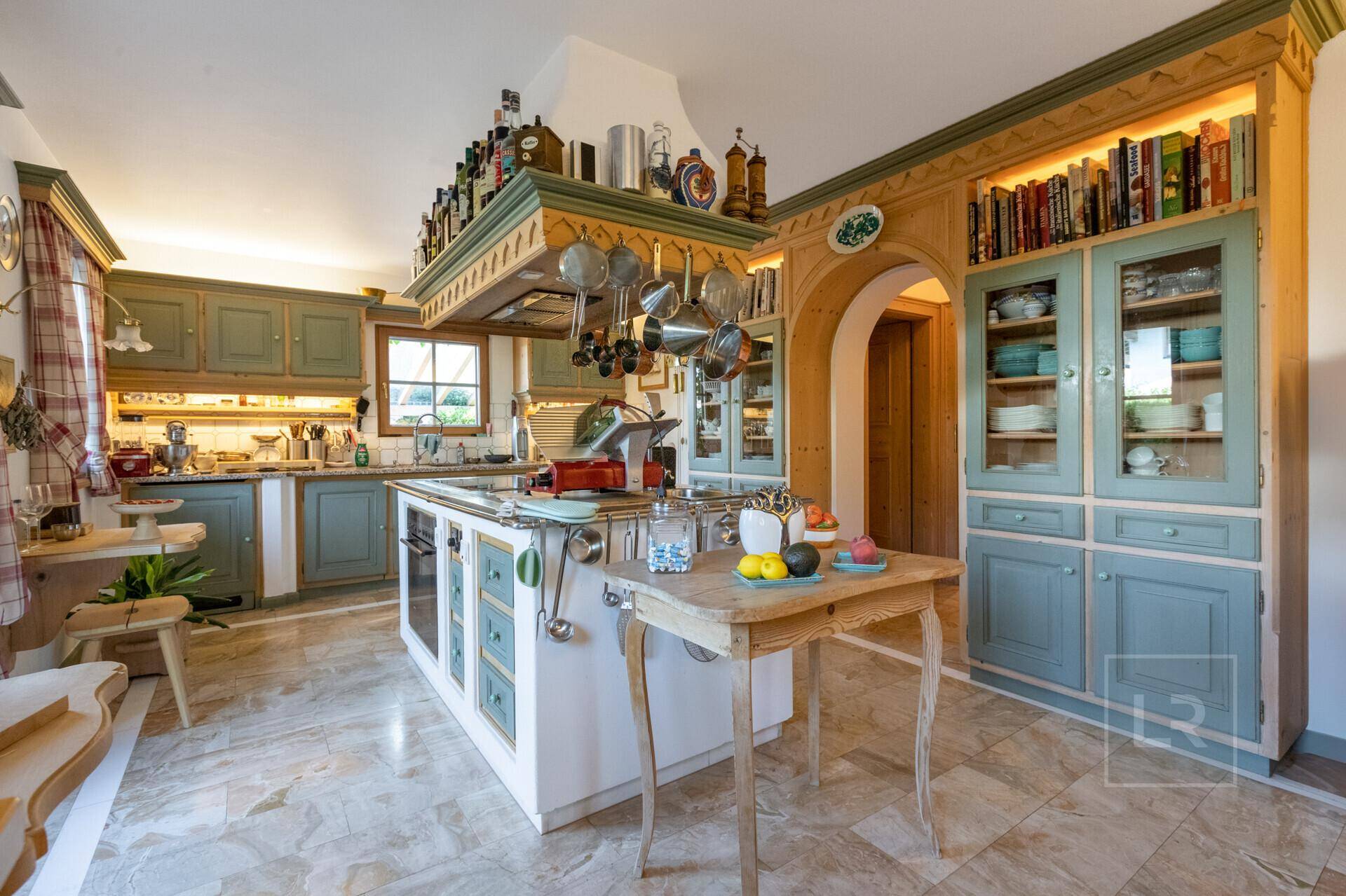 Traditionelle Küche mit hellblauen Schränken, Holzdetails und einer zentralen Kochinsel, sehr gemütlich.