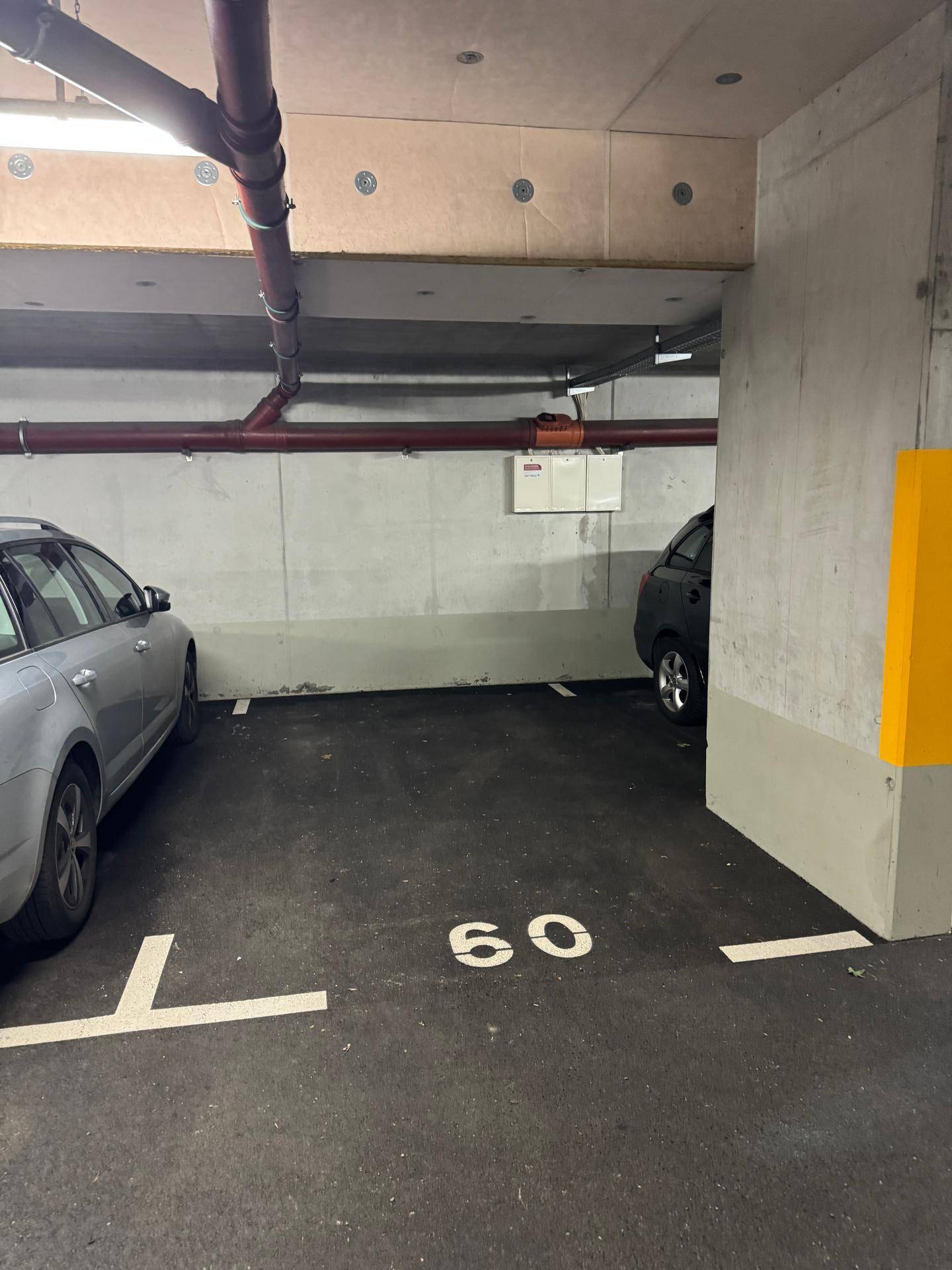 Tiefgaragenstellplatz mit Betonwänden und sichtbaren Leitungen, ideal für ein Fahrzeug.